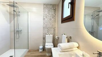 Une salle de bain moderne avec une douche à parois de verre, des toilettes et un lavabo avec un miroir.