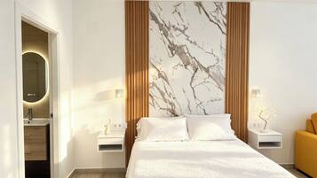 Une chambre d’hôtel moderne avec un lit, des tables de chevet, un miroir et un mur en marbre.
