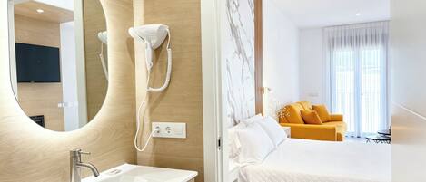 Una habitación de hotel moderna con una cama grande, un baño con lavamanos y espejo, y un teléfono.
