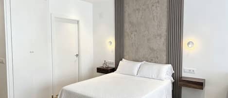 Un dormitorio moderno con una cama grande, un armario y una pared de acento de concreto.