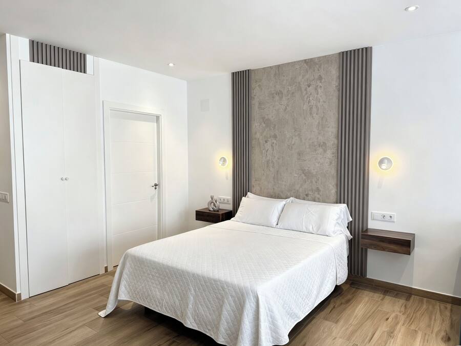 Un dormitorio moderno con una cama grande, un armario y una pared de acento de concreto.