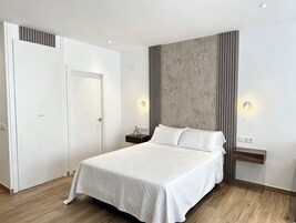 Un dormitorio moderno con una cama grande, un armario y una pared de acento de concreto.