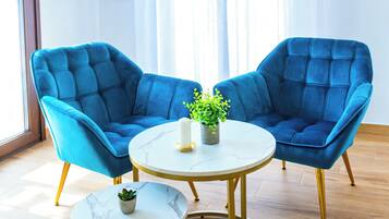 Une pièce avec deux fauteuils bleus, une petite table ronde et une plante en pot.