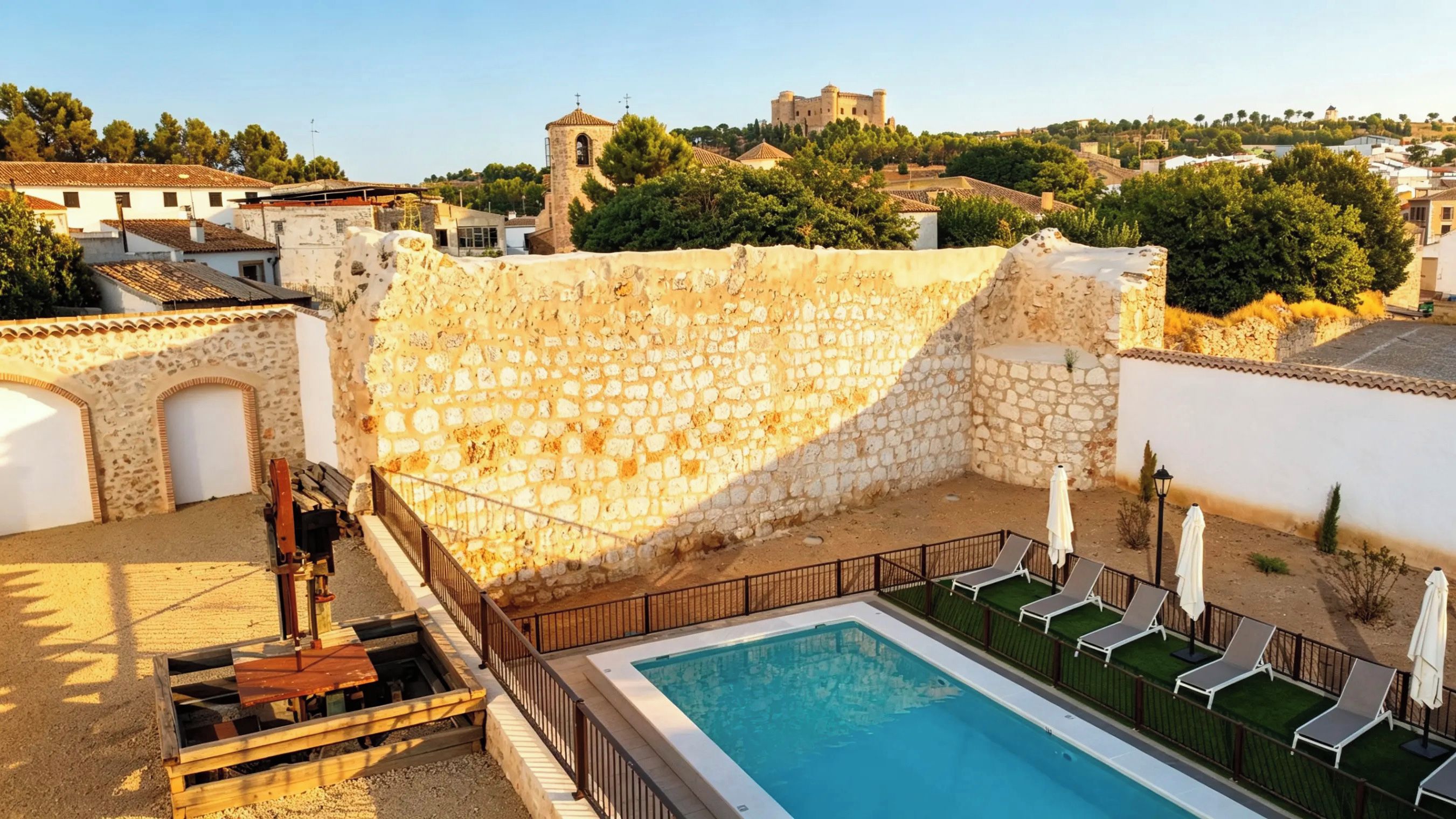 Un área de piscina con muros de piedra, piscina y sillas de descanso.