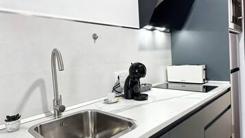 Una cocina moderna con un lavamanos de acero inoxidable, una cafetera y un tostador.
