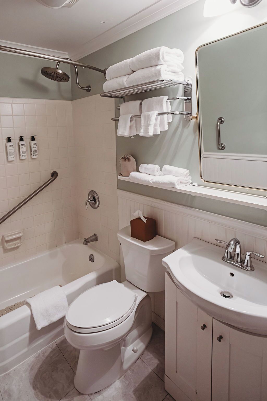 A modern bathroom with a bathtub, toilet, and sink. There are multiple towels and toiletries visible.