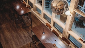 A long dining table with chairs, large windows, and hanging disco balls. - Hideaway Inn Mt. Snow (West Dover)