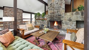 A cozy living room with a stone fireplace, a wooden coffee table, and comfortable seating. - Hideaway Inn Mt. Snow (West Dover)