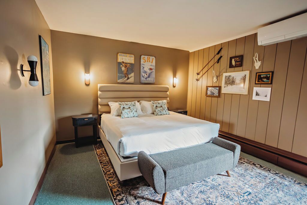 A bedroom with a large bed, a bedside table, a chair, and wall-mounted artwork.