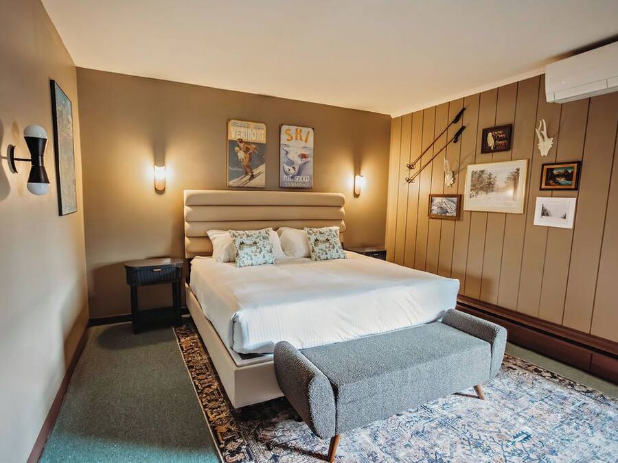 A bedroom with a large bed, a bedside table, a chair, and wall-mounted artwork.