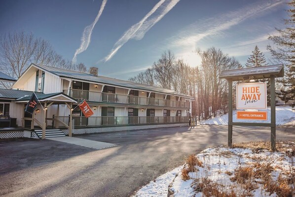 Un hôtel doté d’une entrée couverte, d’un panneau indiquant l’entrée de l’hôtel et d’un panneau « Retraite tranquille ».