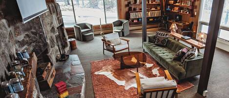 Una sala de estar acogedora con chimenea de piedra, sofá de cuero y una estantería llena de libros y objetos decorativos.