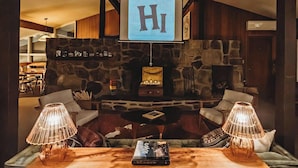 A cozy lounge area with a stone fireplace, comfortable seating, and a 'Hi' sign above. - Hideaway Inn Mt. Snow (West Dover)