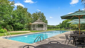 A swimming pool with a gazebo, outdoor seating, and a view of trees. - Hideaway Inn Mt. Snow (West Dover)