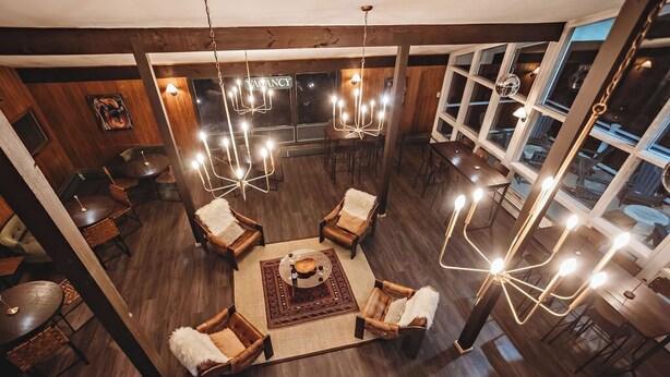 A spacious lounge area with multiple seating options, including sofas and chairs, arranged around a central coffee table. - Hideaway Inn Mt. Snow (West Dover)