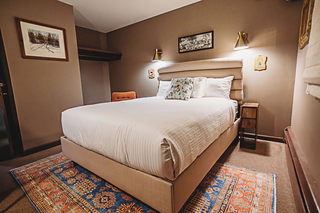 Un dormitorio con una cama grande, una mesita de noche, una silla y una alfombra.