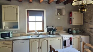 Une cuisine avec des meubles de rangement en bois, une fenêtre, un évier, une cuisinière et une table à manger avec des chaises.