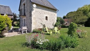 Un bâtiment en pierre, doté d’une antenne parabolique, entouré d’un jardin bien entretenu, agrémenté de fleurs et de pelouse verdoyante.