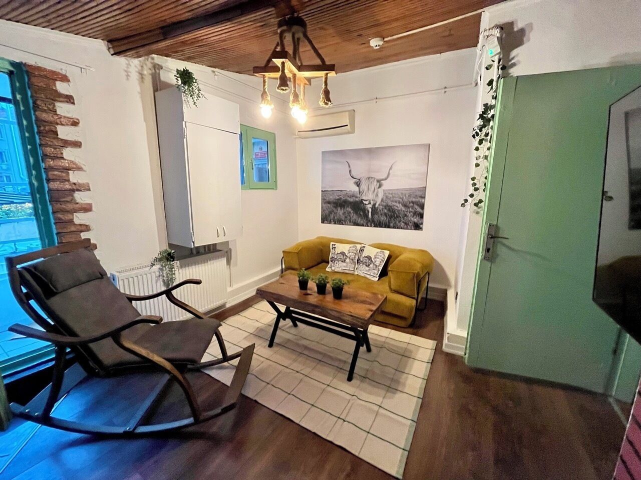 A cozy living room with a rocking chair, a yellow sofa, and a coffee table.