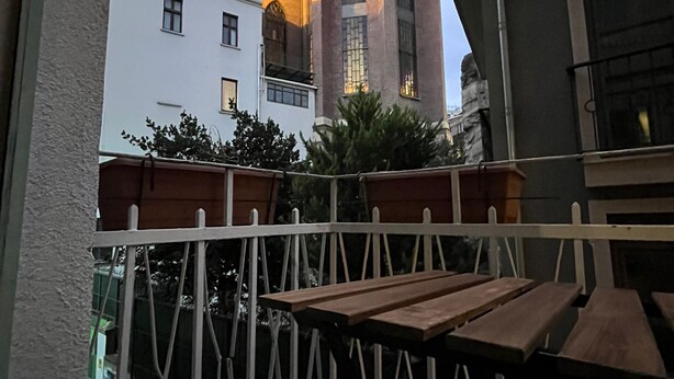A balcony with a view of a church with a tall tower and arched windows. - Palmy Istiklal (İstanbul)