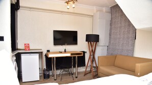 A compact hotel room with a kitchenette, a flat-screen TV, a sofa, and a standing lamp. - Palmy Istiklal (İstanbul)
