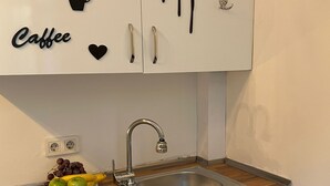 A kitchen with white cabinets, a stainless steel sink, and a wooden countertop. There are decorative items like a teapot, a cup, and utensils on the wall. - Palmy Istiklal (İstanbul)