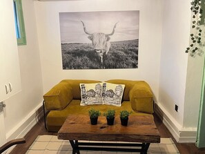 A room with a sofa, a coffee table with potted plants, a wall-mounted picture of a bull, and a window with a green frame. - Palmy Istiklal (İstanbul)