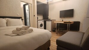 A bedroom with a bed, a washing machine, a TV, and a small table. - Palmy Istiklal (İstanbul)