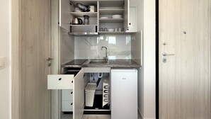 Uma cozinha compacta com lava-louças embutida, uma pia e um frigorífico pequeno.
