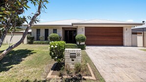 Une maison moderne à deux étages, dotée d’un garage, d’une pelouse bien entretenue et d’une boîte aux lettres.