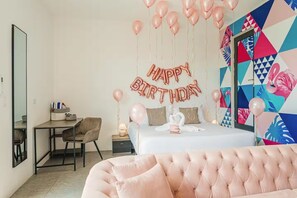 Une chambre avec un lit, un bureau et une chaise. On y voit des ballons et une pancarte avec l’inscription « Joyeux anniversaire ».