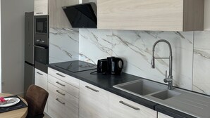 Eine moderne Küche mit Einbauofen, Mikrowelle und einer eleganten, schwarzen Kaffeemaschine auf der Arbeitsplatte.