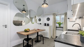 Une cuisine moderne avec une table en bois, des tabourets noirs, un évier et un grand miroir.