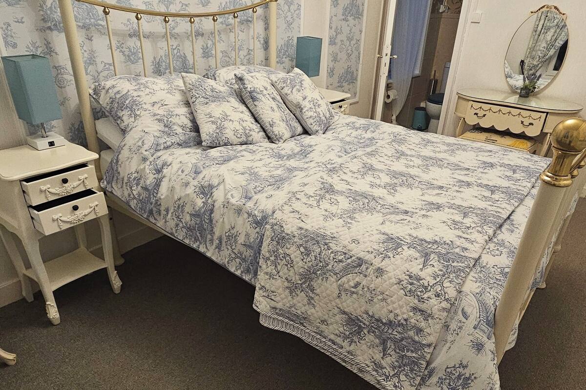 A bedroom with a bed, nightstand, dresser, and a mirror.