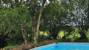 A wooden deck with a pool, surrounded by greenery. - The Lions Den - La Loge Mantilly (Mantilly)