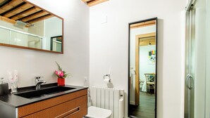 Une salle de bain moderne avec un lavabo noir, des toilettes blanches et un grand miroir.