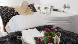 Une chambre d’hôtel bien rangée, avec un lit, un lavabo blanc et une petite salle de bain.