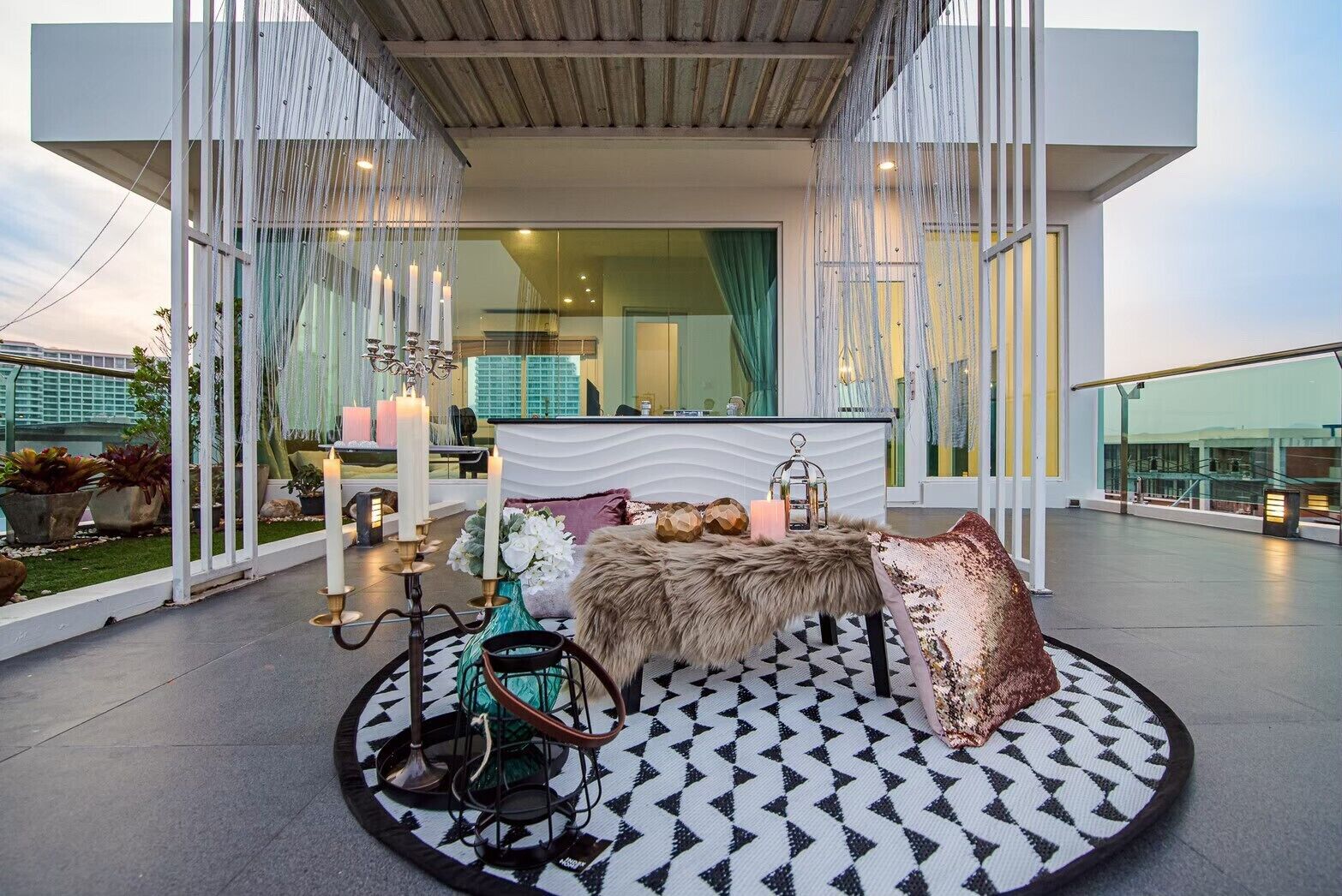 Een moderne buitenruimte met een ronde tafel, kaarsen en decoratieve accessoires.