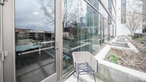 A modern building with large glass windows, a seating area with chairs, and a small garden with plants. - Kenect Nashville (Nashville)