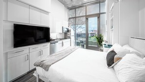 A modern bedroom with a large bed, a TV, and a balcony with a view. - Kenect Nashville (Nashville)