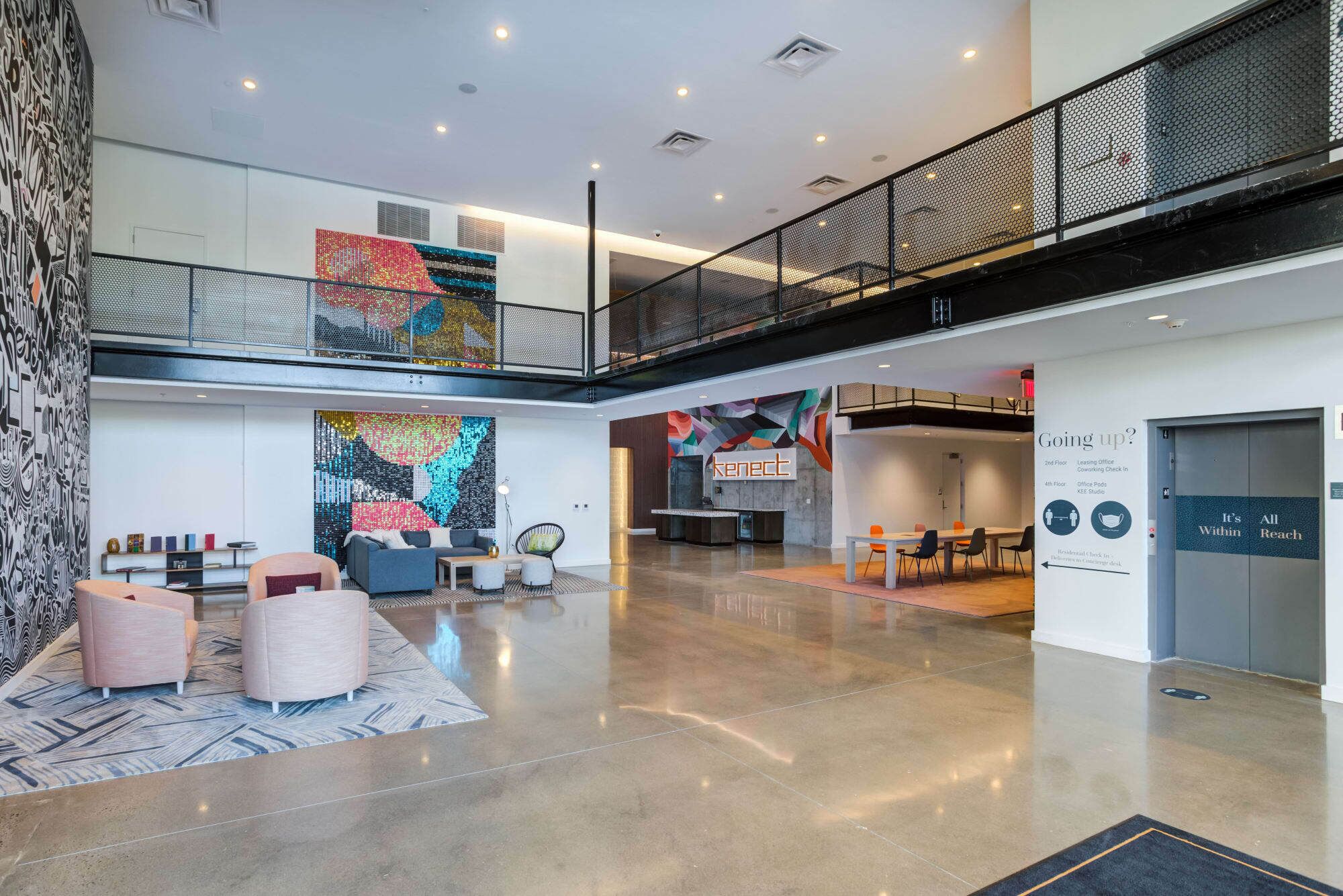A spacious lobby with a high ceiling, a mezzanine level, and a seating area with modern furniture.