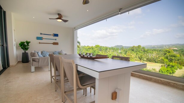 Una cocina moderna con una isla grande, zona de estar y vistas a un paisaje exuberante.