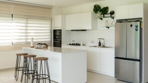 Una cocina moderna con una isla central, electrodomésticos de acero inoxidable y taburetes de bar.