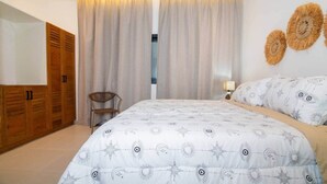 Ein Schlafzimmer mit einem Bett, einem Sessel, einem Kleiderschrank und einer Wand mit Dekoration.