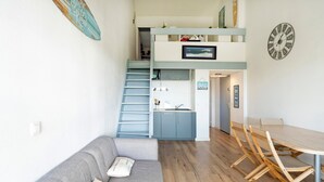 Un espace de vie compact comprenant un canapé, une table à manger et un coin cuisine.