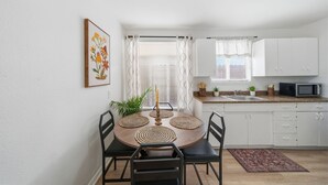 A compact kitchen with white cabinets, a microwave, and a dining area with a round table and chairs. - Stay just minutes from Downtown in this cozy, well-designed 1-bedroom apartment. An ideal base for professionals, students, and travelers wanting fast access to Houston’s best dining and attractions. (Houston)
