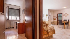 A hallway leading to a dining area with a table and chairs, a radiator, and a door with a patterned curtain. - Casa Paola (Alezio)