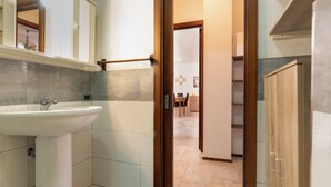 A bathroom with a sink, mirror, and wooden door leading to a hallway. - Casa Paola (Alezio)