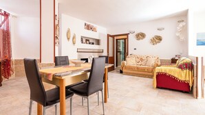 A dining area with a wooden table and chairs, a sofa, and decorative wall art. - Casa Paola (Alezio)