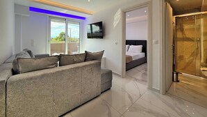 Ein modernes Hotelzimmer mit einer Couch, einem Bett, einem Fernseher und einem Balkon mit Blick.